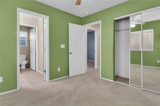 unfurnished bedroom featuring light carpet, a closet, ceiling fan, and ensuite bathroom