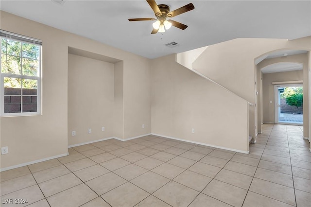 tiled empty room featuring ceiling fan and plenty of natural light