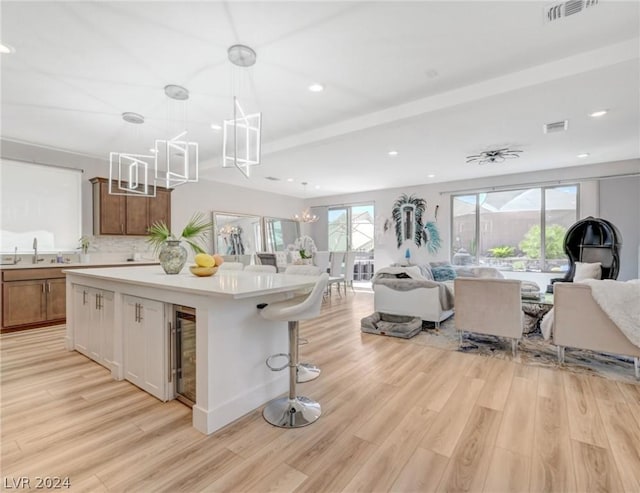 kitchen with hanging light fixtures, light hardwood / wood-style flooring, a center island, and a chandelier