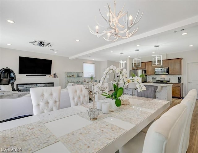 dining space with beam ceiling and light hardwood / wood-style flooring