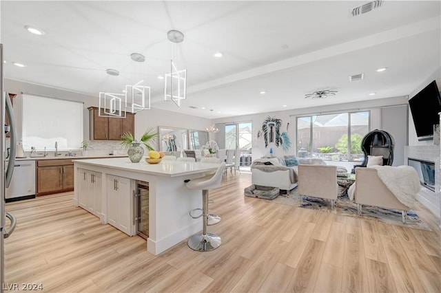 kitchen featuring a kitchen island, pendant lighting, a chandelier, a kitchen breakfast bar, and light wood-type flooring