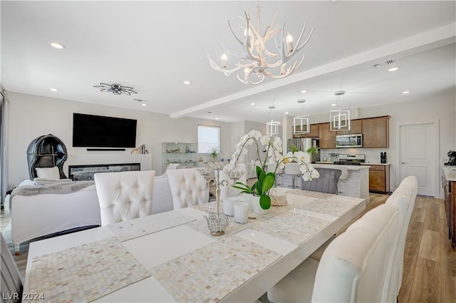 dining space with beamed ceiling, an inviting chandelier, and light hardwood / wood-style floors