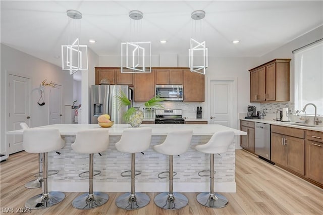 kitchen featuring appliances with stainless steel finishes, decorative light fixtures, sink, a breakfast bar area, and a center island