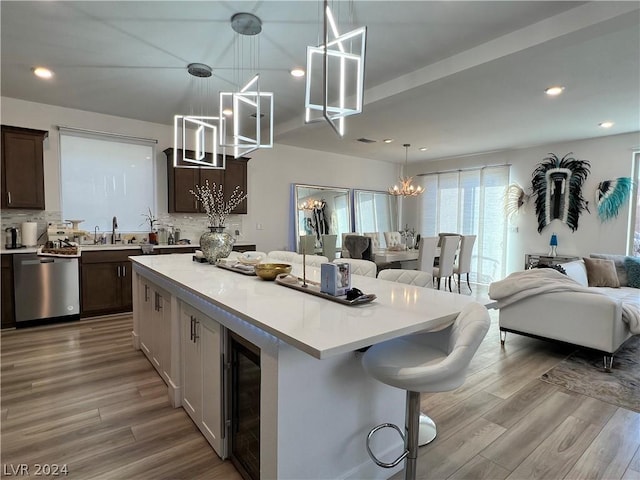 kitchen featuring pendant lighting, a breakfast bar, an inviting chandelier, a kitchen island, and stainless steel dishwasher