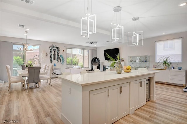 kitchen featuring white cabinetry, decorative light fixtures, light hardwood / wood-style floors, and a kitchen island