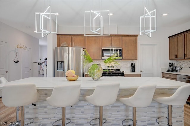 kitchen with pendant lighting, decorative backsplash, a breakfast bar area, and stainless steel appliances