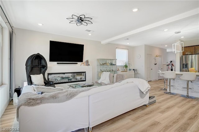 living room featuring beam ceiling and light hardwood / wood-style flooring