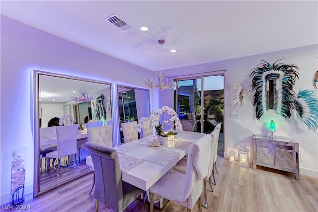 dining area with light wood-type flooring and a chandelier