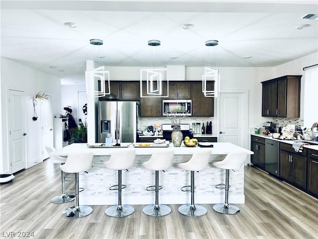 kitchen with stainless steel appliances, a center island, a kitchen breakfast bar, and dark brown cabinetry