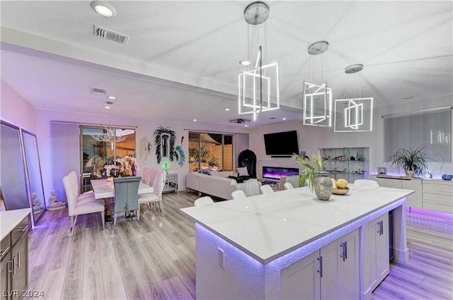 kitchen with pendant lighting, white cabinetry, light wood-type flooring, and a kitchen island