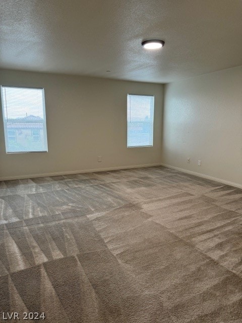 carpeted empty room with a textured ceiling