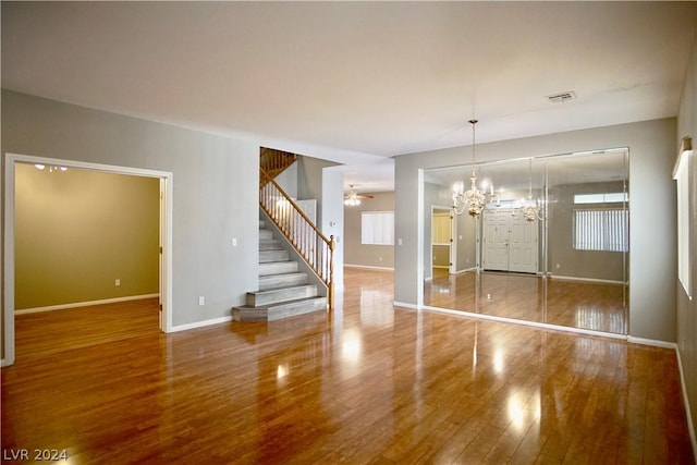 spare room with ceiling fan with notable chandelier and hardwood / wood-style floors