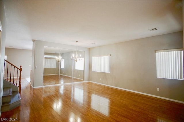 spare room with hardwood / wood-style floors and a chandelier