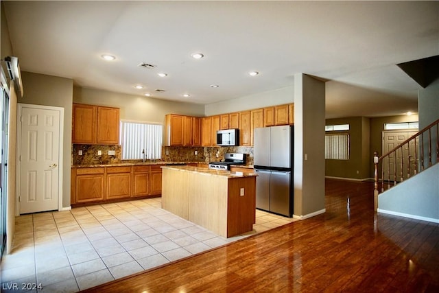 kitchen featuring sink, light tile patterned floors, stainless steel appliances, tasteful backsplash, and a kitchen island