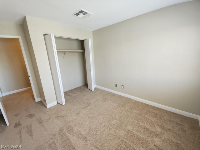 unfurnished bedroom with light colored carpet and a closet