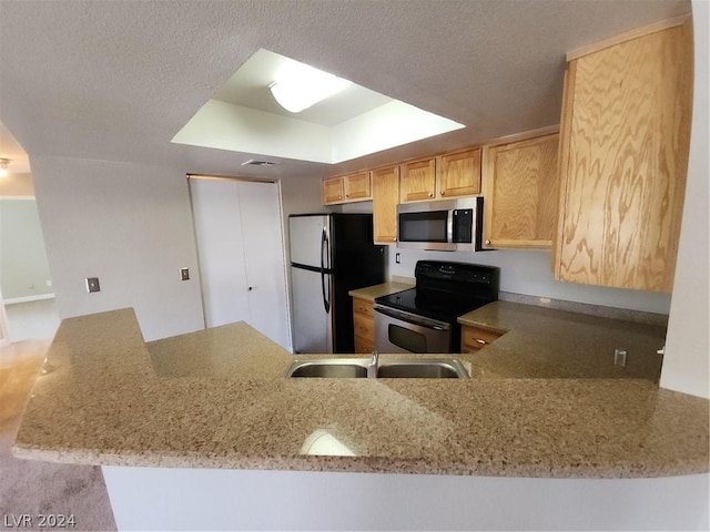 kitchen featuring sink, appliances with stainless steel finishes, light stone counters, light brown cabinetry, and kitchen peninsula