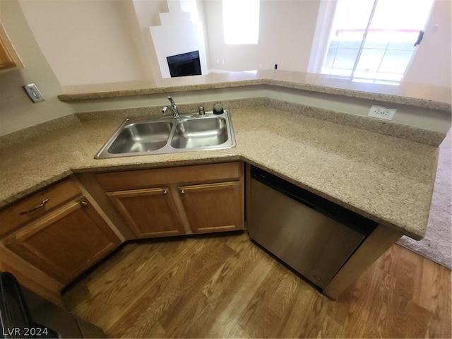 kitchen with kitchen peninsula, dishwasher, sink, and light hardwood / wood-style flooring