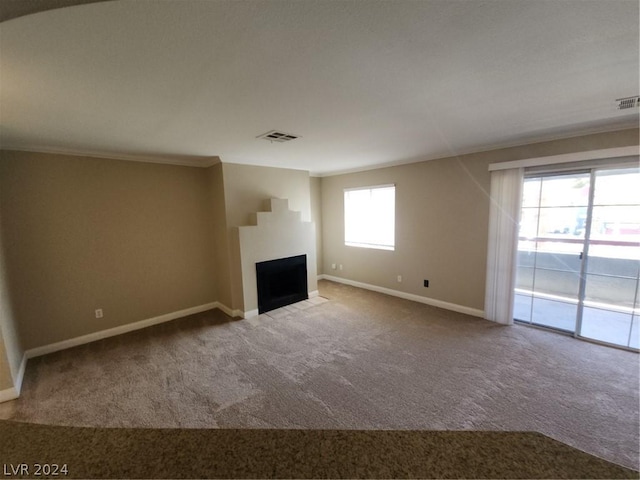 unfurnished living room with a wealth of natural light, carpet floors, and ornamental molding