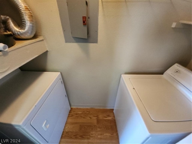 clothes washing area with washer and dryer, dark wood-type flooring, and electric panel