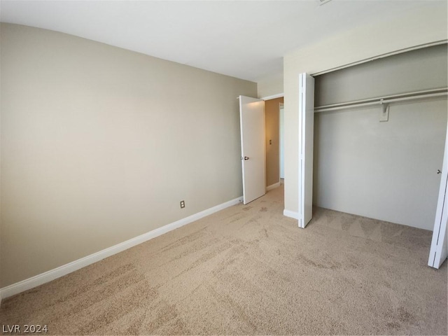 unfurnished bedroom with light colored carpet and a closet