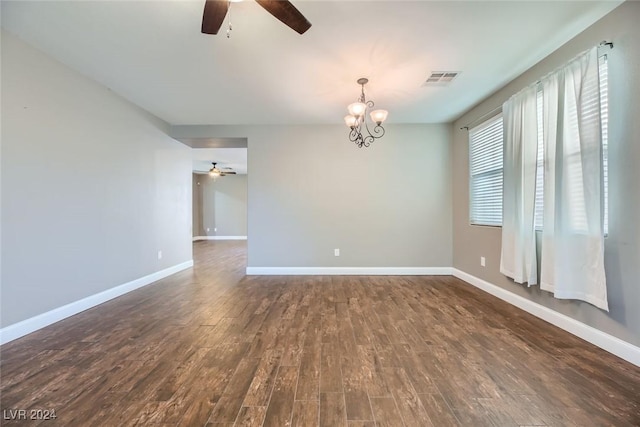 empty room with dark hardwood / wood-style flooring and ceiling fan with notable chandelier