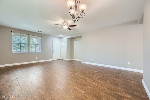 spare room with dark hardwood / wood-style floors and ceiling fan with notable chandelier