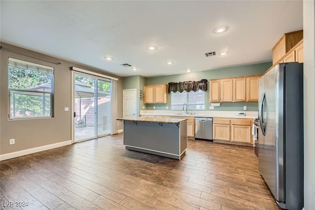 kitchen with a kitchen island, appliances with stainless steel finishes, wood-type flooring, sink, and light brown cabinets