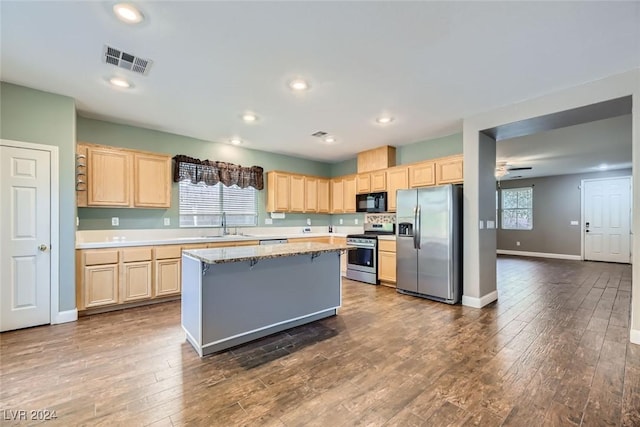 kitchen with stainless steel appliances, a center island, light brown cabinets, and dark hardwood / wood-style floors