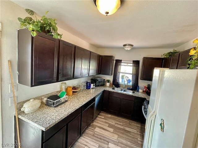 kitchen with dark brown cabinetry, sink, dishwasher, white refrigerator with ice dispenser, and light hardwood / wood-style floors