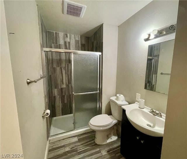 bathroom with vanity, hardwood / wood-style flooring, a shower with shower door, and toilet