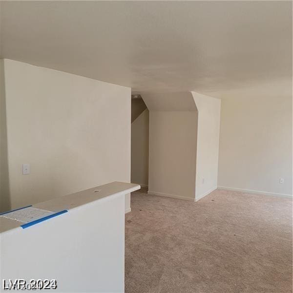 bonus room with baseboards, light carpet, and vaulted ceiling