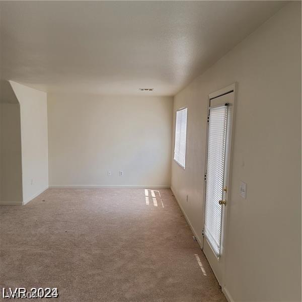 unfurnished room featuring visible vents, light carpet, and baseboards