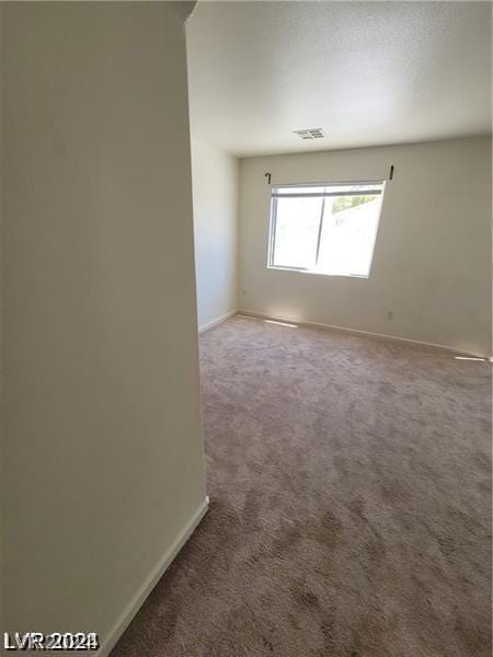 empty room featuring visible vents, baseboards, and carpet flooring