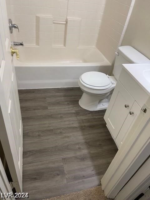 full bathroom featuring vanity, wood-type flooring, washtub / shower combination, and toilet