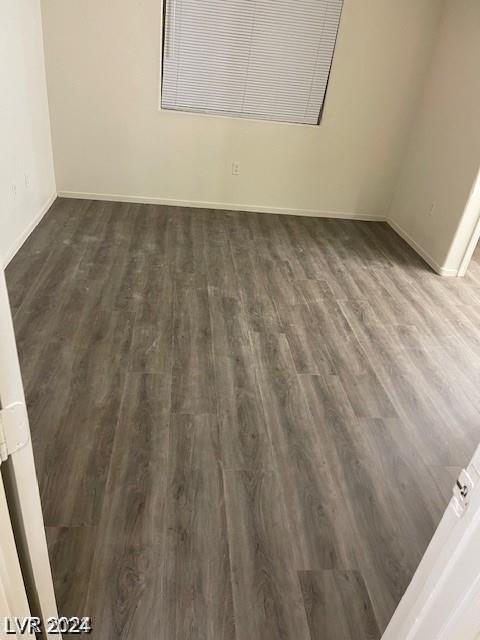 empty room featuring baseboards and dark wood-style flooring