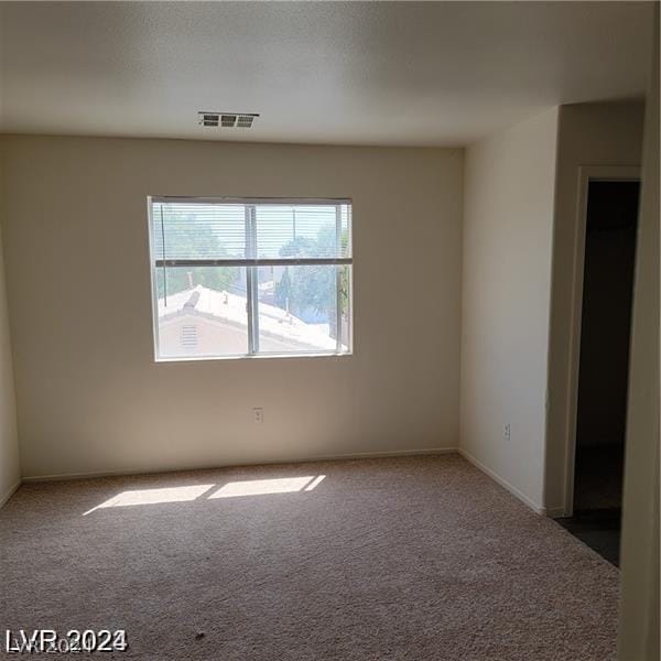 empty room featuring carpet flooring, baseboards, and visible vents