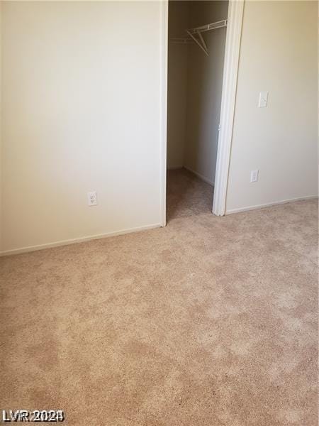 unfurnished bedroom featuring a closet, baseboards, and light colored carpet