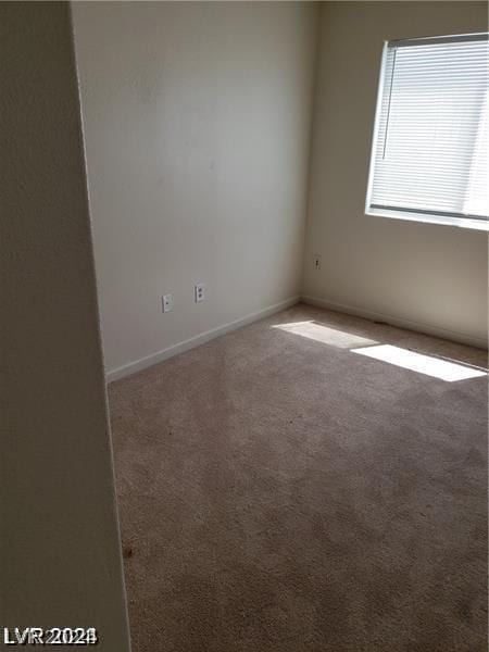 empty room featuring light colored carpet and baseboards