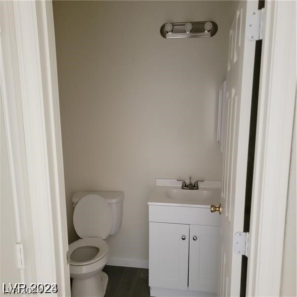 bathroom with hardwood / wood-style floors, toilet, and vanity