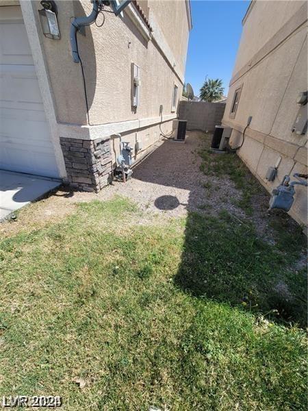 view of yard featuring a garage, central AC unit, and fence