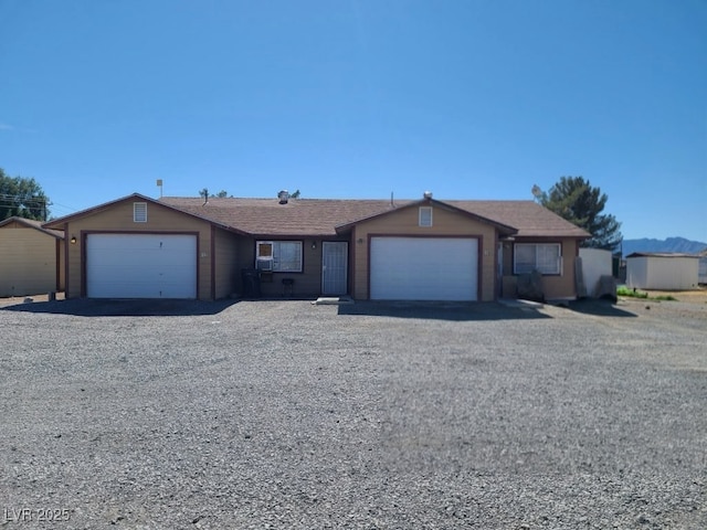 ranch-style house featuring a garage and gravel driveway