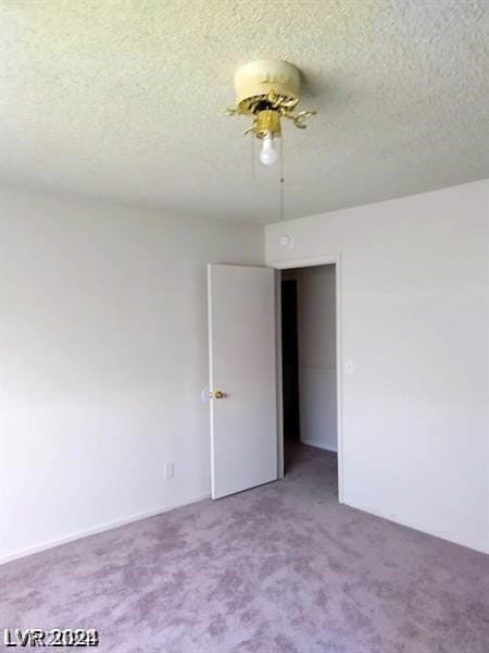 empty room featuring a textured ceiling, ceiling fan, and carpet flooring