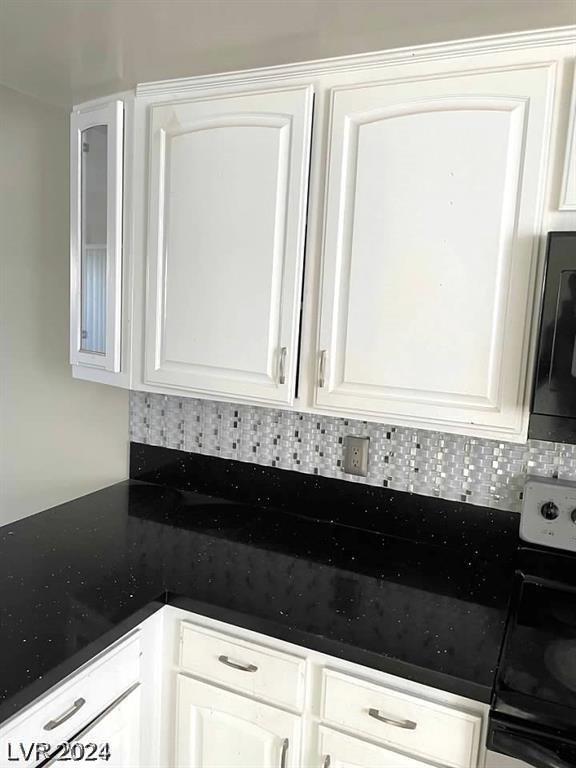 kitchen featuring stove, backsplash, and white cabinets