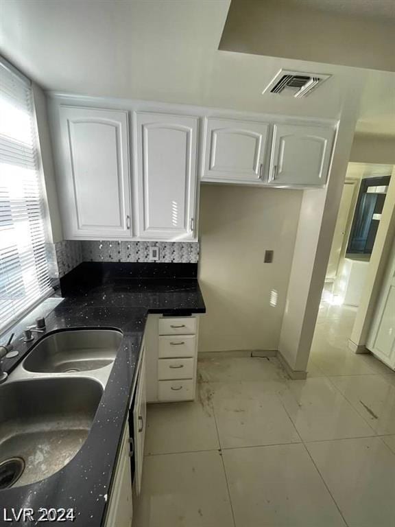 kitchen featuring sink, light tile patterned floors, and white cabinets