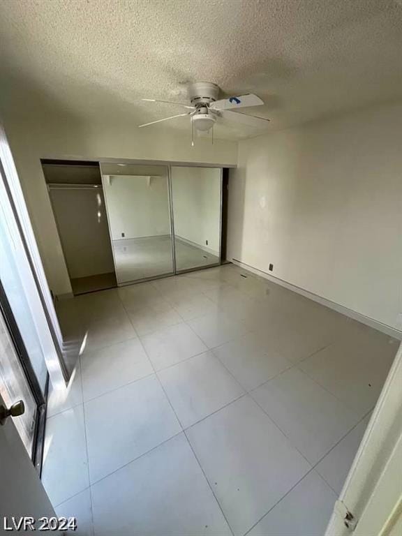 unfurnished bedroom featuring a textured ceiling, ceiling fan, and a closet