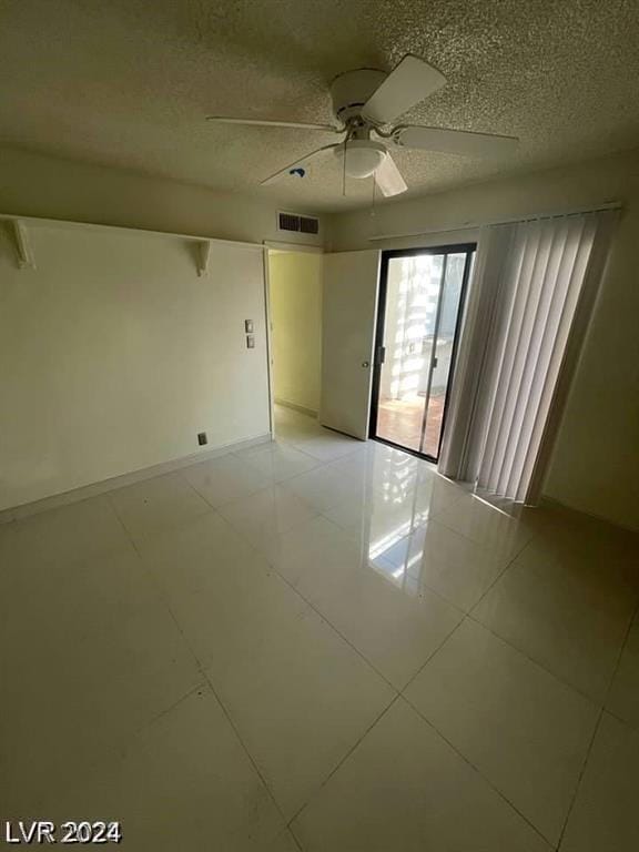 unfurnished room with ceiling fan, light tile patterned floors, and a textured ceiling