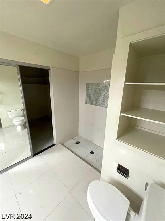 bathroom featuring a shower, tile patterned floors, and toilet