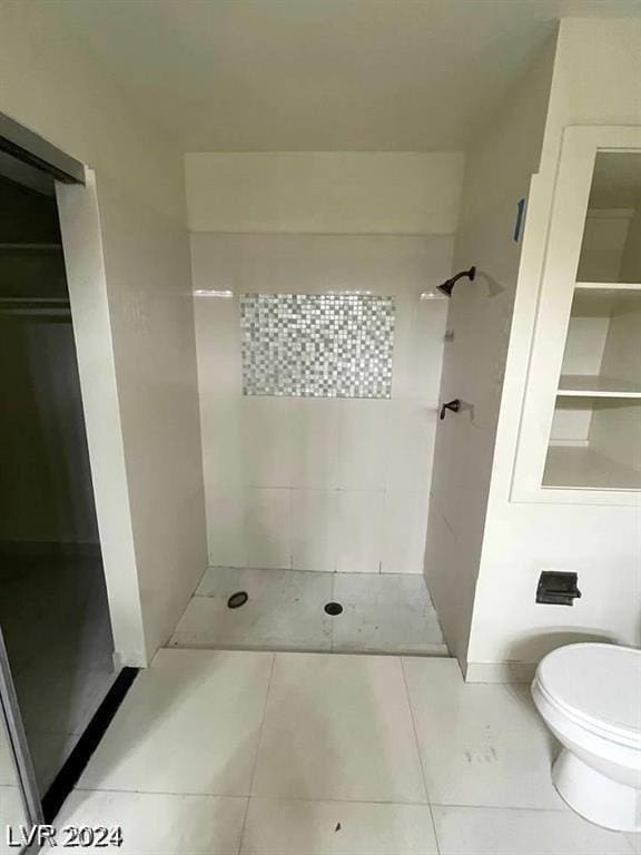 bathroom featuring tile patterned flooring, tiled shower, and toilet