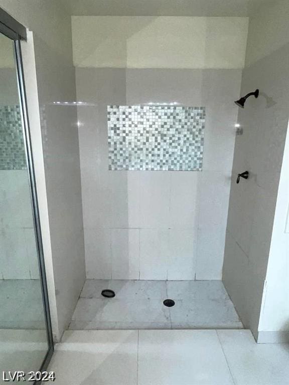 bathroom with a tile shower and tile patterned flooring