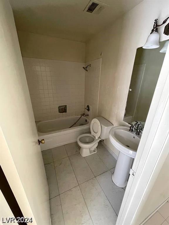 full bathroom with tiled shower / bath, sink, toilet, and tile patterned flooring